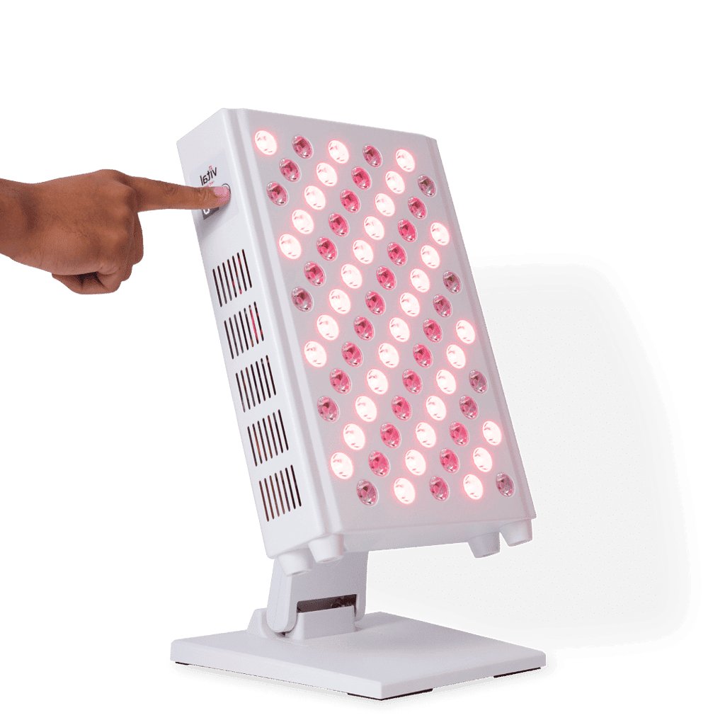 A hand presses the button on a sleek, rectangular light therapy device, its multiple illuminated red lights showcasing the rejuvenating red light therapy benefits. The device is elegantly mounted on a stand, ready to enhance wellbeing.